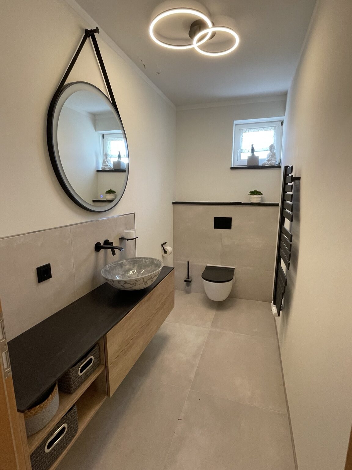 Modernes Badezimmer mit rundem Spiegel, Waschtisch und WC